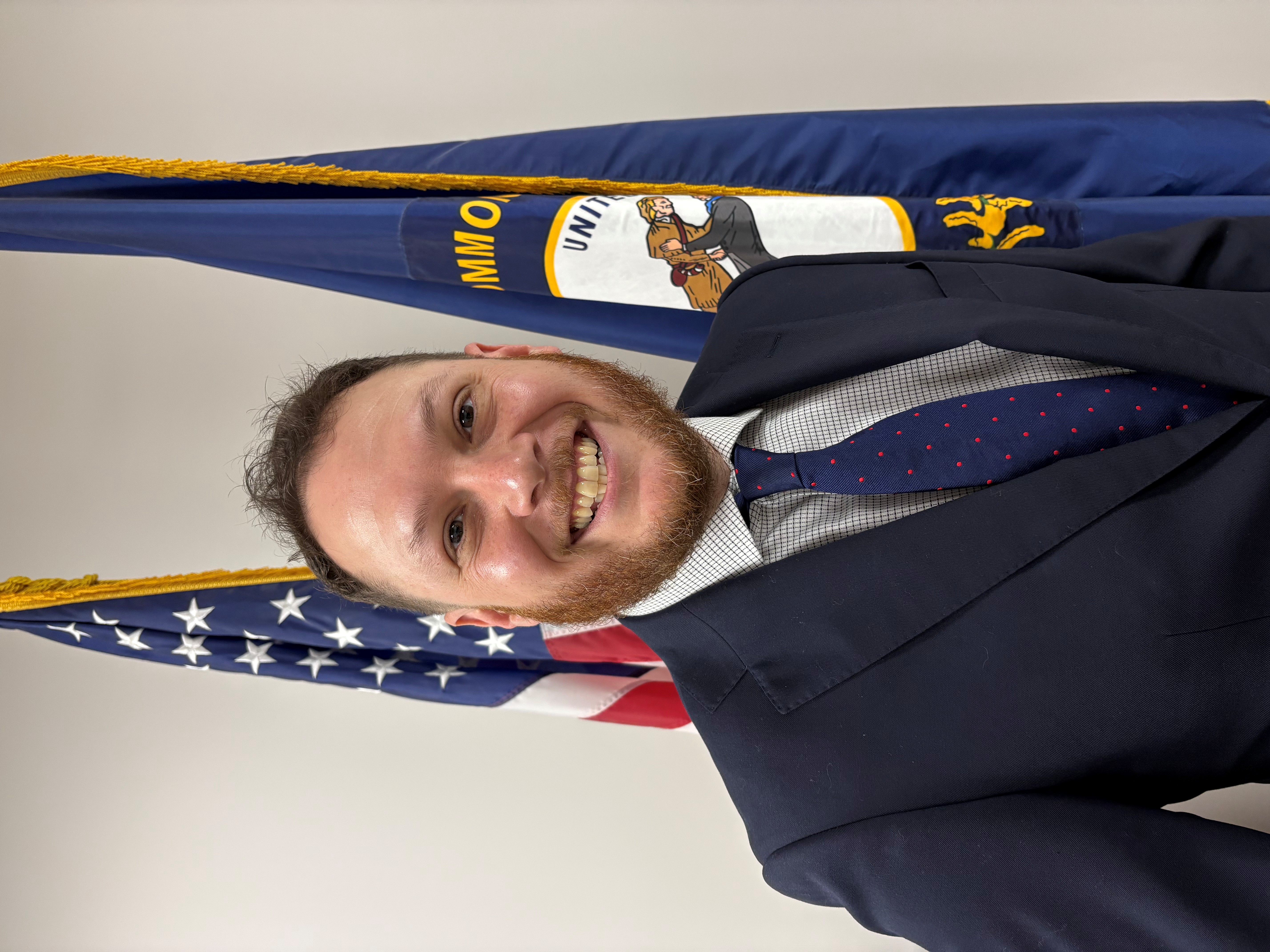 Portrait of Nick Storm in front of the American and Kentucky flags.